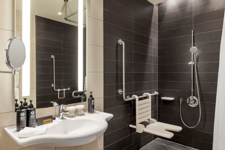 a picture showing a shower with hand rails and a chair